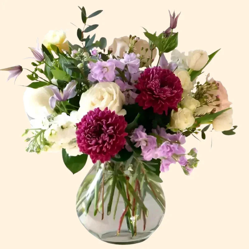 Elegant bouquet with blush dahlia, white roses, purple flowers in clear glass vase