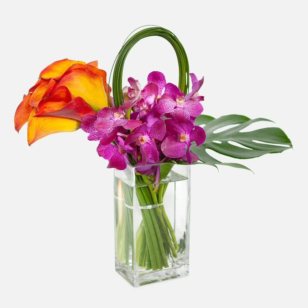 Amazing Kona Flowers with orange calla lilies, purple orchids, and tropical greenery in a glass vase, same-day Manhattan & NYC delivery.