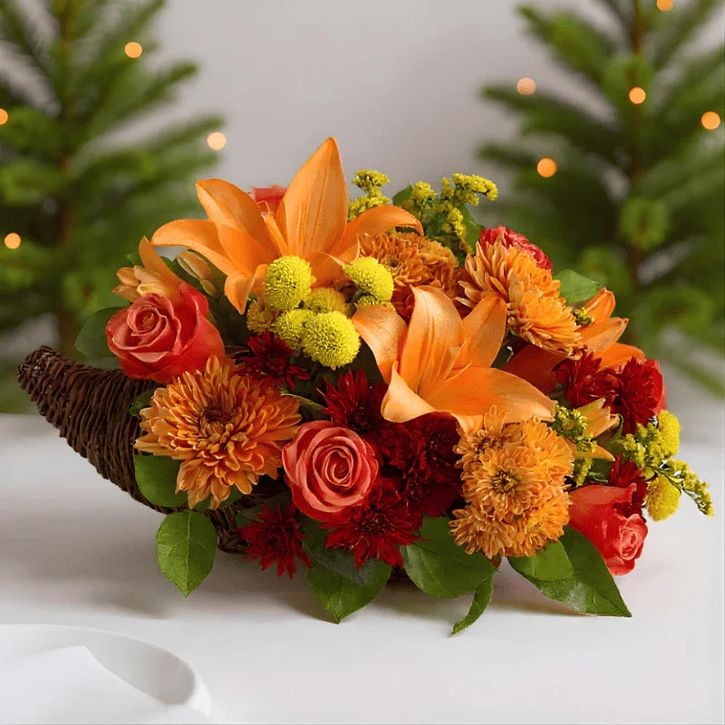 Colorful autumn flower cornucopia centerpiece with orange lilies, roses, chrysanthemums, and yellow accents