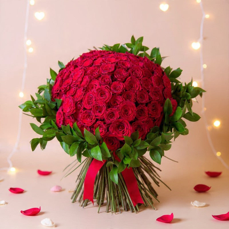 Premium 100 stem red rose bouquet featuring one hundred fresh long-stem red roses beautifully hand-tied with lush greenery, creating a luxurious floral gift for anniversaries, Valentine's Day, proposals, birthdays, and romantic celebrations.