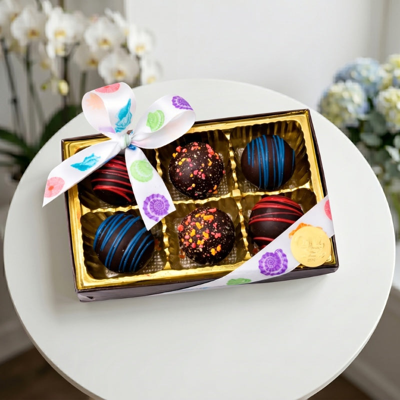 Assorted handcrafted chocolate truffles in a luxury gift box with colorful decorations, perfect for gifting and special occasions.