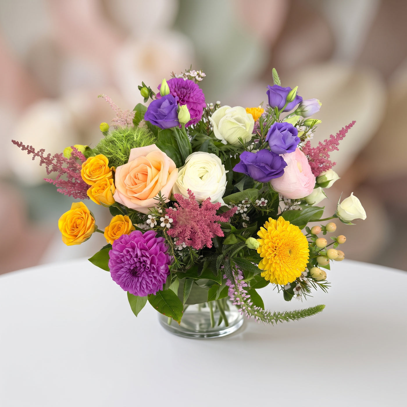 Dahlia Sunset colorful floral arrangement with purple dahlias, peach and orange roses, yellow blooms and seasonal greenery