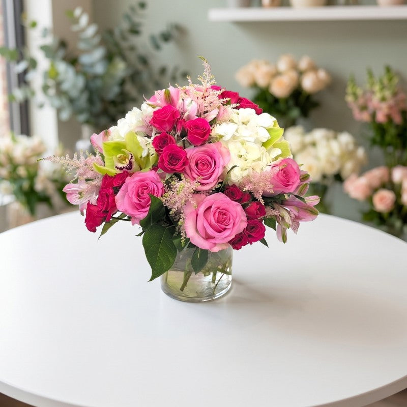 Elegant pink rose and white hydrangea floral arrangement in clear glass vase on white table