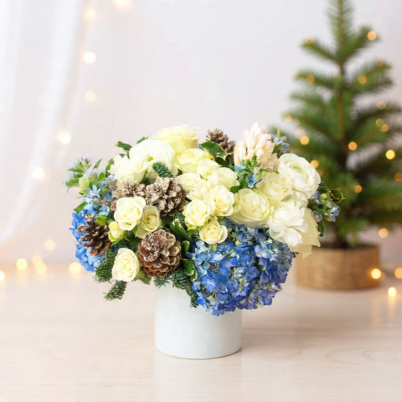 Ivory roses, snapdragons, pinecones, berries, and winter greenery arranged for a natural rustic winter bouquet.