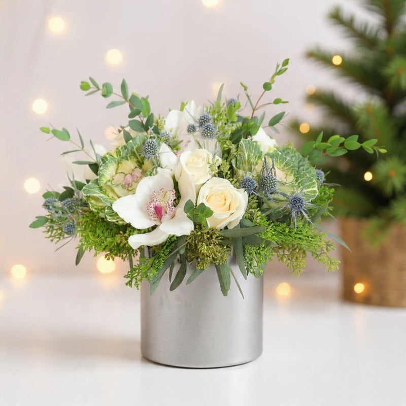 White roses, hydrangeas, pine, and winter greenery arranged in a soft snowy bouquet for elegant winter floral décor.