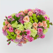 floral arrangement with peach roses, pink carnations, green chrysanthemums, and purple flowers on white background