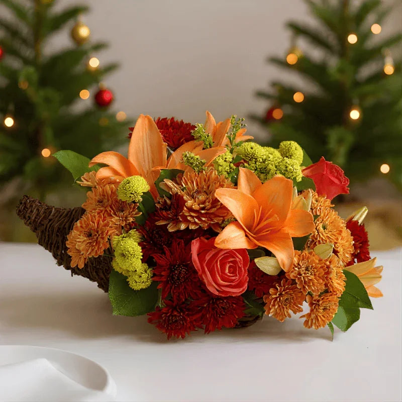Autumn floral centerpiece with orange lilies, roses, chrysanthemums, and green accents in a woven cornucopia basket