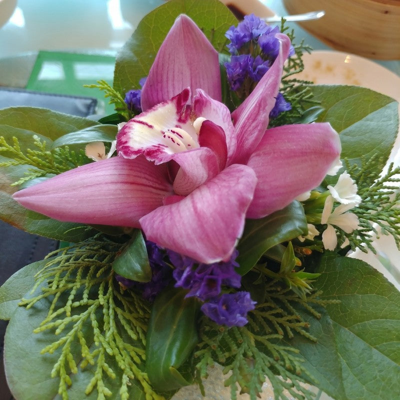 Elegant wristlet corsage with white roses, purple orchids, silver ribbon, and green leaves