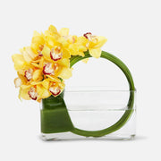 Yellow cymbidium orchid bouquet with green stems arranged in a clear rectangular vase with water