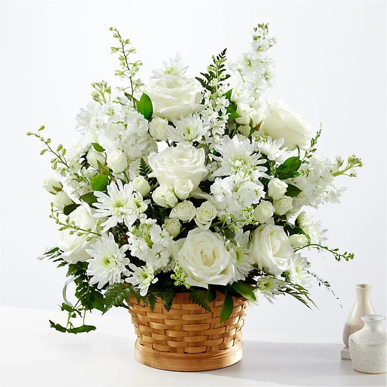 Elegant white rose and chrysanthemum sympathy flower arrangement in woven basket for condolences