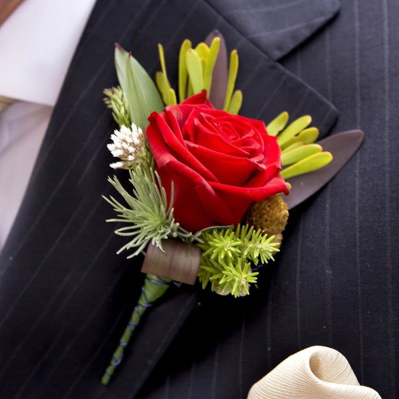 Red rose boutonniere with green leaves and small yellow buds, wrapped stem with pearl pins