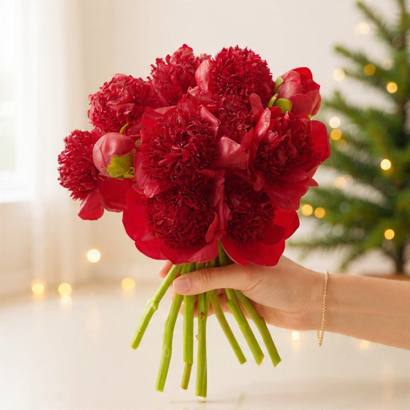 Handheld bouquet of vibrant red peonies with full layered petals, arranged for luxury holiday gifting and festive décor.