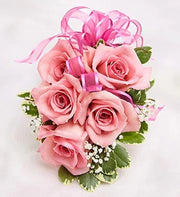 Pink rose corsage with five roses, green variegated leaves, white baby's breath, and pink ribbon bow