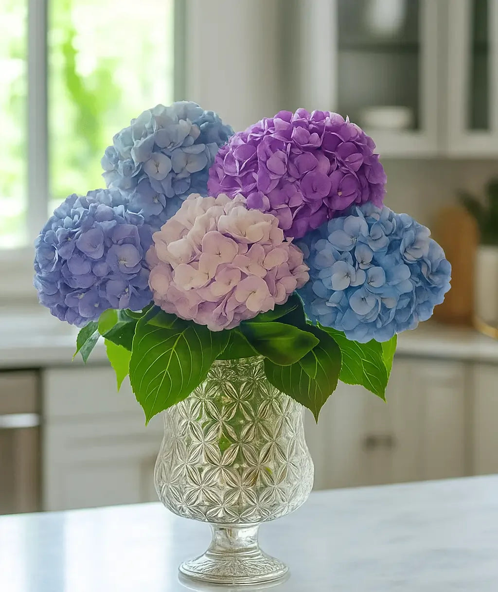 Elegant bouquet of blue, purple, and pink hydrangeas in a textured silver vase on kitchen counter