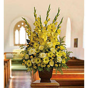 Elegant yellow floral arrangement with gladiolus, roses, and daisies in a church setting