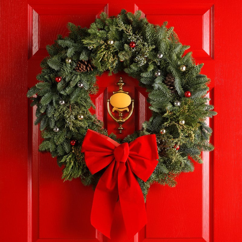 Classic Red Bow Christmas Door Wreath with pine foliage, ornaments, pinecones, and a large velvet red bow on a festive front door.
