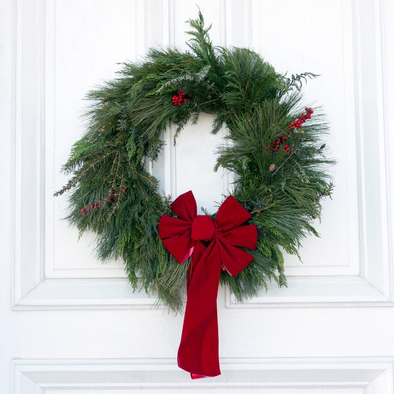 Elegant Red Velvet Christmas Wreath with lush green foliage, winter berries, and a long velvet bow for classic holiday door décor.